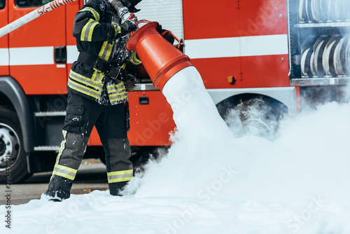 Canvas Print cropped shot of firefighter extinguishing fire with foam on street