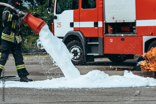 Photography partial view of firefighter extinguishing fire with foam on street