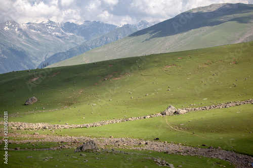 A shephard walks through mountainous landscape in Himalayas photo