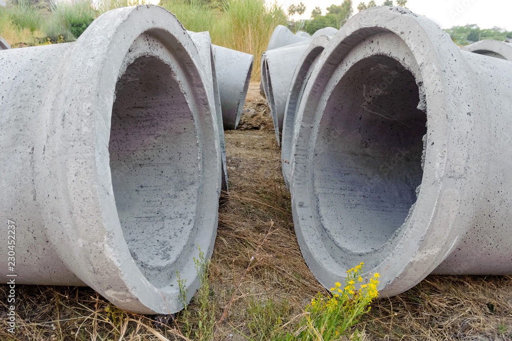 New concrete pipes (rings) are on the ground. Two pipes lie in the foreground