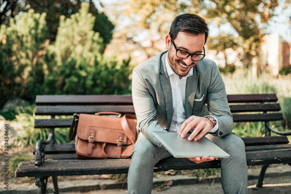 Happy elegant men sitting on a bench with a laptop. Happy elegant men sitting on a bench with a laptop.