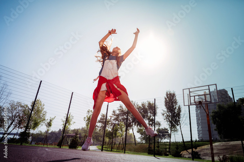 Try to catch. Joyful female person raising arms while trying to catch ball