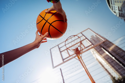 City activity. Active teenager raising hands while playing basketball © Viacheslav Yakobchuk