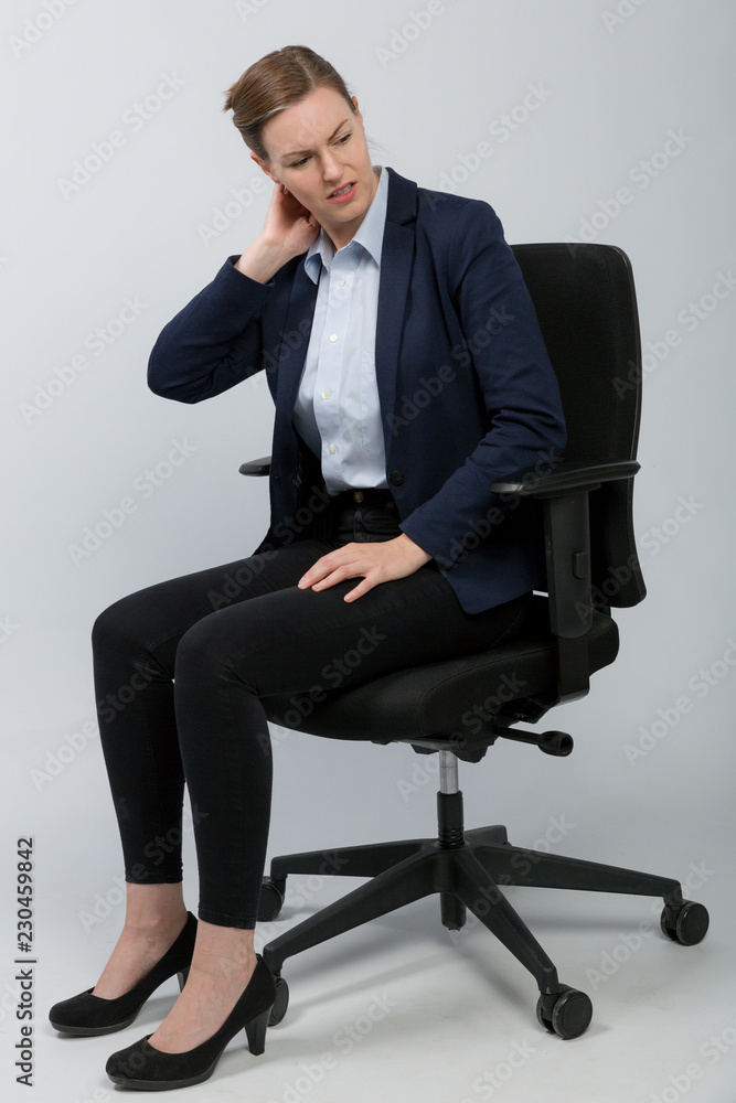 Frau im Blazer auf einem Bürostuhl hält sich den Nacken Frau im Blazer auf einem Bürostuhl hält sich den Nacken