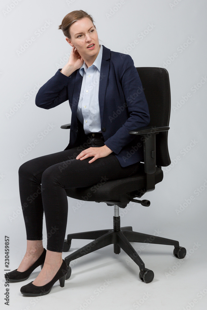 Frau im Blazer auf einem Bürostuhl hält sich den Nacken Frau im Blazer auf einem Bürostuhl hält sich den Nacken