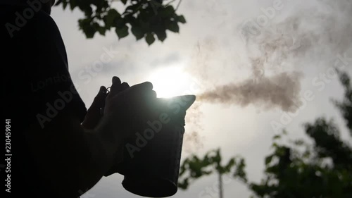 HD beekeeper pressing the bee smoker and produces smoke photo