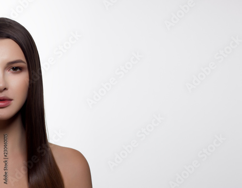 Close-up portrait of a young woman with straight brown hair looking at the camera and smiling. lean skin, day makeup. Spa procedures, skin care, cosmetology, injections, hair lamination, beauty