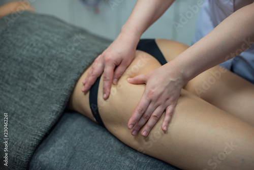 A professional masseuse does an anti-cellulite massage of the client   s buttocks. Massage the hips. Masseur doing anti-cellulite hand massage on the back of the thigh in the spa