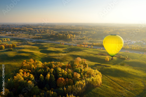 Colorful hot air balloon flying over forest surrounding Vilnius city on sunny autumn evening.
