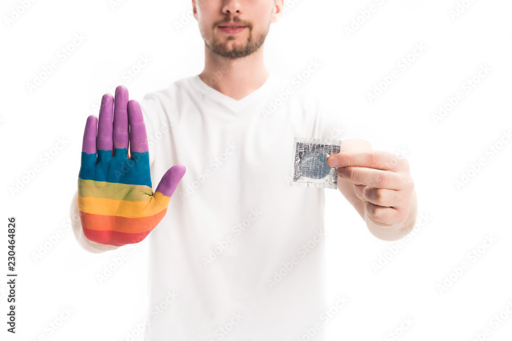 cropped image of homosexual man with hand painted in rainbow holding condom isolated on white, world aids day concept cropped image of homosexual man with hand painted in rainbow holding condom isolated on white, world aids day concept