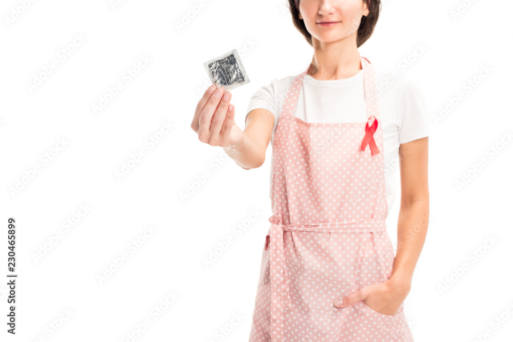cropped image of housewife in pink apron and red ribbon showing condom isolated on white, world aids day concept cropped image of housewife in pink apron and red ribbon showing condom isolated on white, world aids day concept