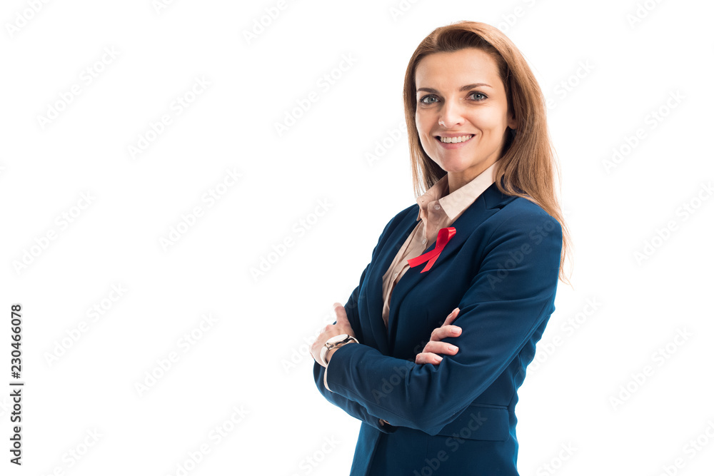 smiling attractive businesswoman with red ribbon on suit standing with crossed arms isolated on white, world aids day concept smiling attractive businesswoman with red ribbon on suit standing with crossed arms isolated on white, world aids day concept