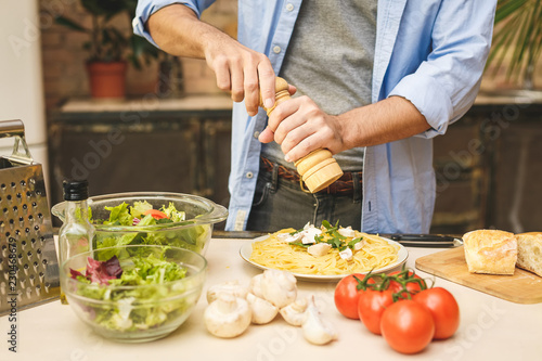 Close-up of young man preparing delicious and healthy food in the home kitchen on a sunny day.