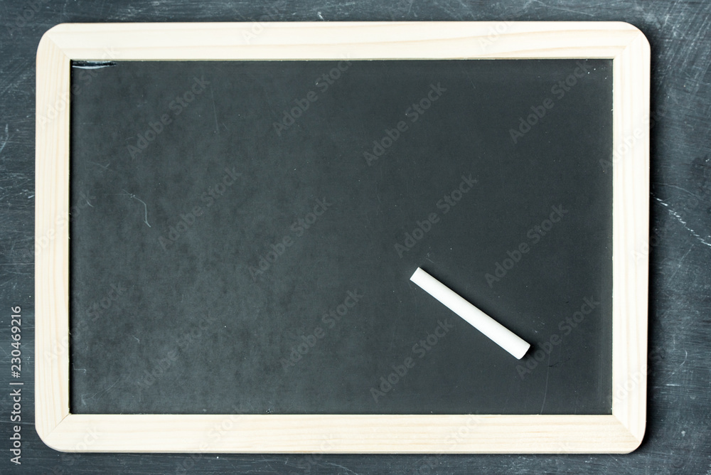 Empty black chalkboard with white chalk on a black, rustic wooden wall