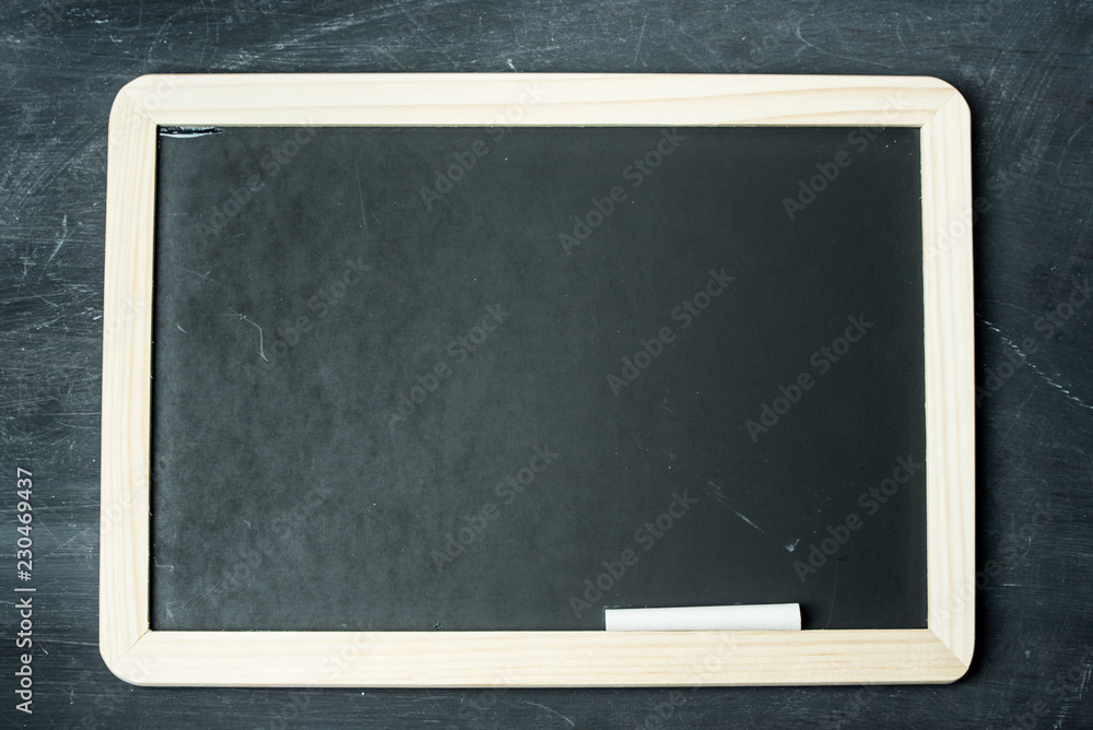 Empty black chalkboard with white chalk on a black, rustic wooden wall Empty black chalkboard with white chalk on a black, rustic wooden wall