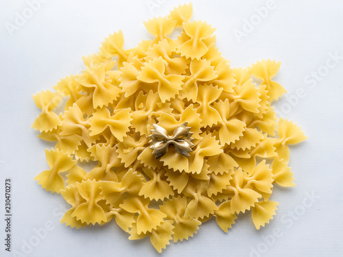 Yellow pasta with golden one in the centre at white background.