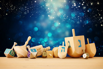 Banner of jewish holiday Hanukkah with wooden dreidels (spinning top) over glitter shiny background.