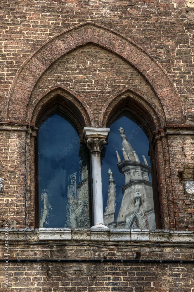Siena Cathedral reflected in arched windows of facing building, Tuscany