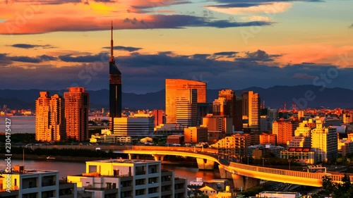 Fukuoka, Japan. A sunset video with a view of central Fukuoka, Japan, with tall modern buildings standing by the Hakata Bay on a cloudy summer day. Time-lapse from day to night, zoom in