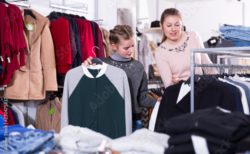 Glad teen girl looking for clothing with mum © JackF
