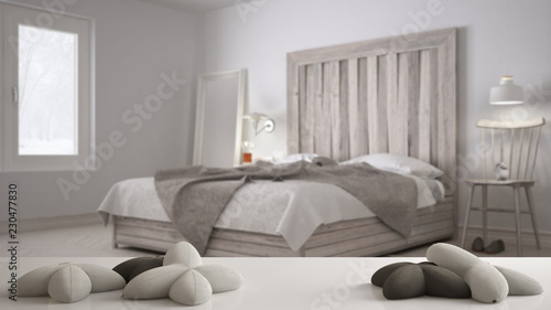 White table, desk or shelf with five soft white pillows in the shape of stars or flowers, over blurred bedroom, bed with wooden headboard, minimal architecture interior design concept