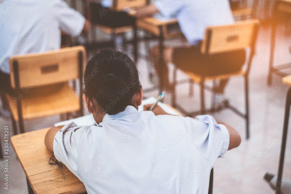 School students taking exam writing answer in classroom with stress School students taking exam writing answer in classroom with stress