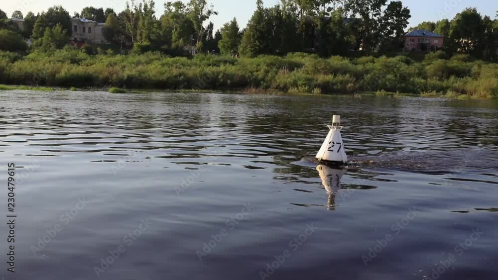 White buoy on the river waves on the background of the forest on the shore White buoy on the river waves on the background of the forest on the shore
