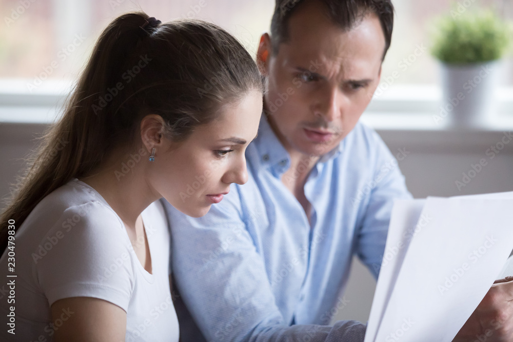 Stressed spouses read letter document notification about unpaid bills taxes or unexpected expenses or due debt. Couple feels frustrated and confused. Bankruptcy lack of money financial problem concept Stressed spouses read letter document notification about unpaid bills taxes or unexpected expenses or due debt. Couple feels frustrated and confused. Bankruptcy lack of money financial problem concept