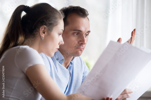 Stressed spouses read letter receive notice about unpaid bills taxes, forfeits. Close up of frustrated wife and husband have financial problems unexpected expenses. Bankruptcy lack of money concept photo