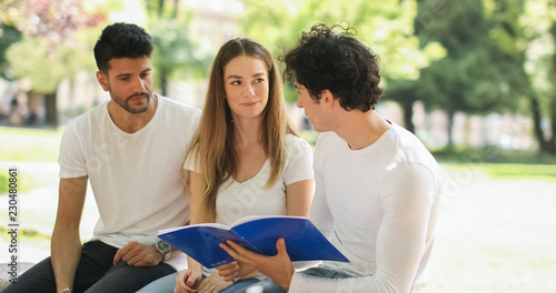 Three students studying together sitting on a bench outdoor