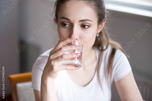 Close up portrait pensive serious millennial woman holding glass drink still water. Beautiful healthy pensive female on diet starting day with fresh natural water healthy lifestyle good habit concept