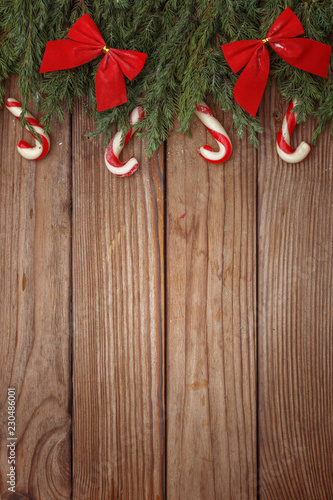 Christmas composition of tree branches, candies and decorations on wooden background. Top view. Copy space.