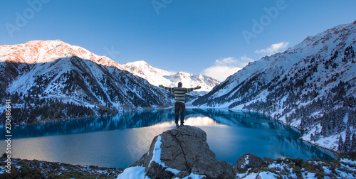 man on top of a mountain on a background of winter mountain lake,Big Almaty Lake, Kazakhstan © serikbaib