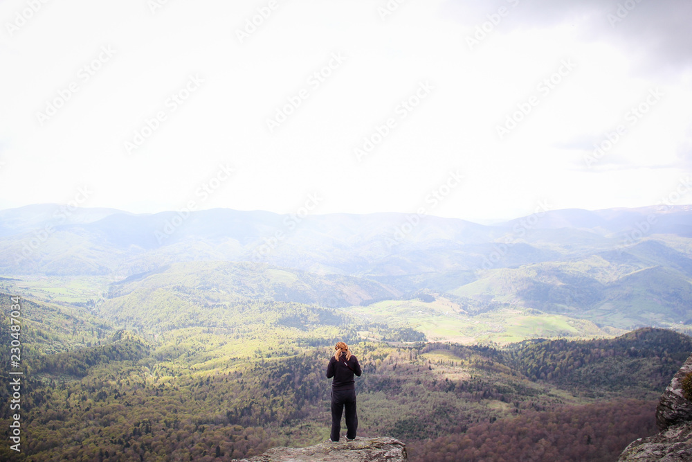 The girl sits on the edge of a cliff with a view of the mountains. Ukrainian Carpathian Mountains. Traveling