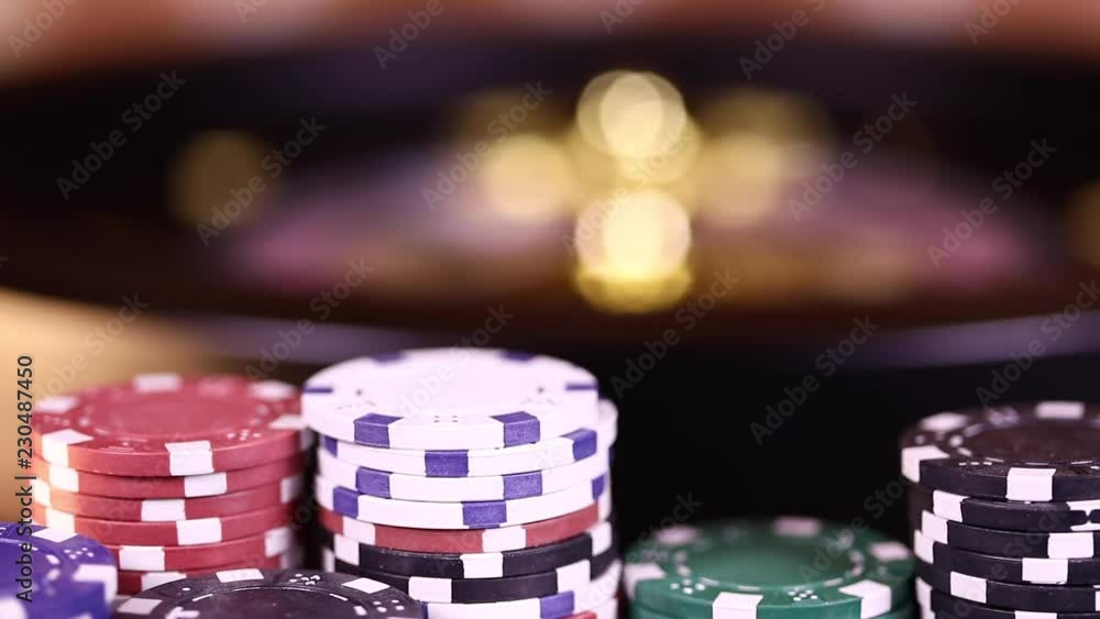 Poker Chips on gaming table, roulette wheel in motion Poker Chips on gaming table, roulette wheel in motion