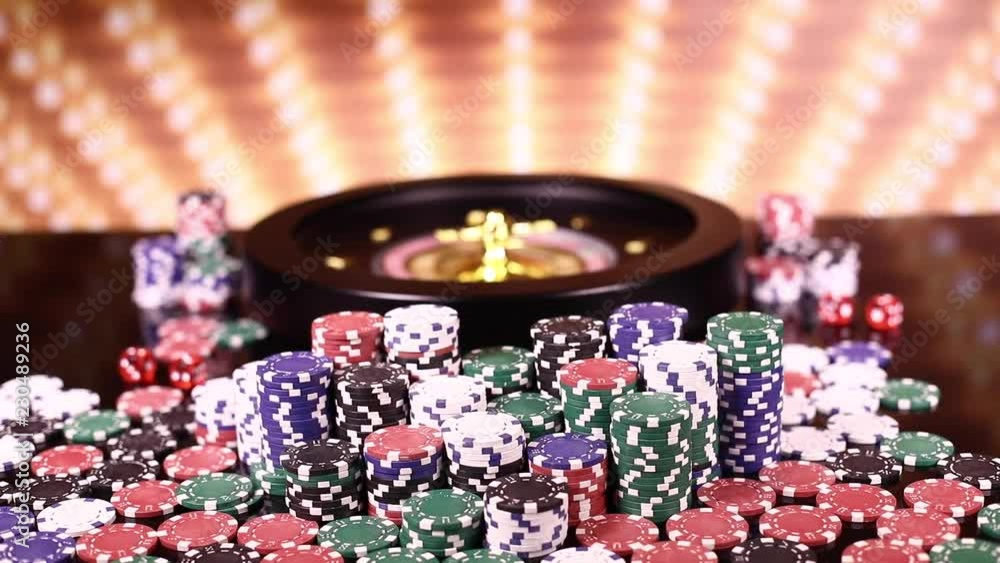 Poker Chips on gaming table, roulette wheel in motion Poker Chips on gaming table, roulette wheel in motion
