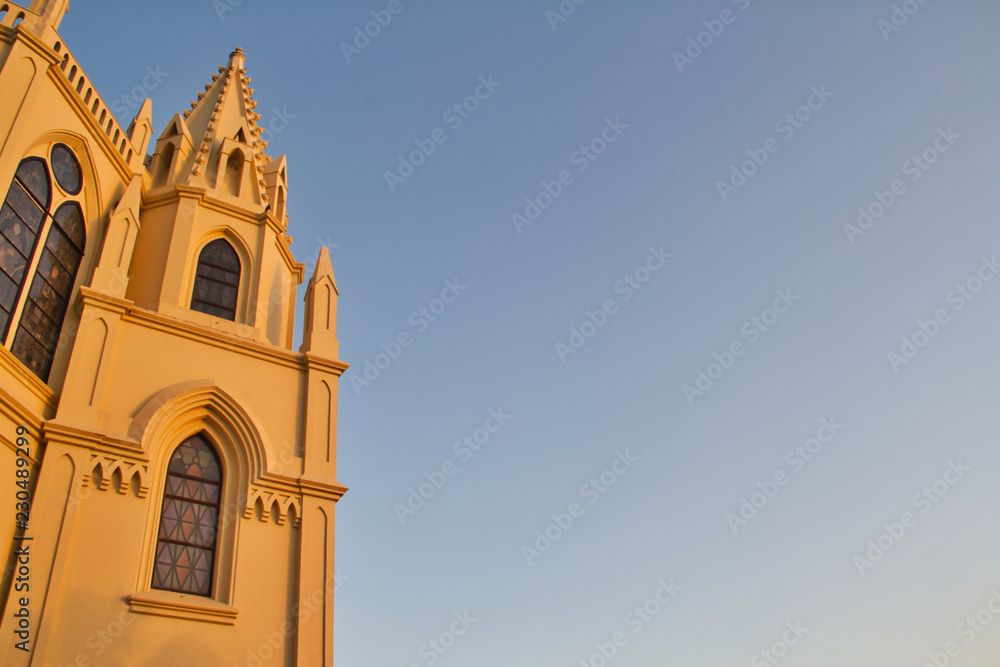 A church reflecting the golden color of evening light with an empty sky for copy space.