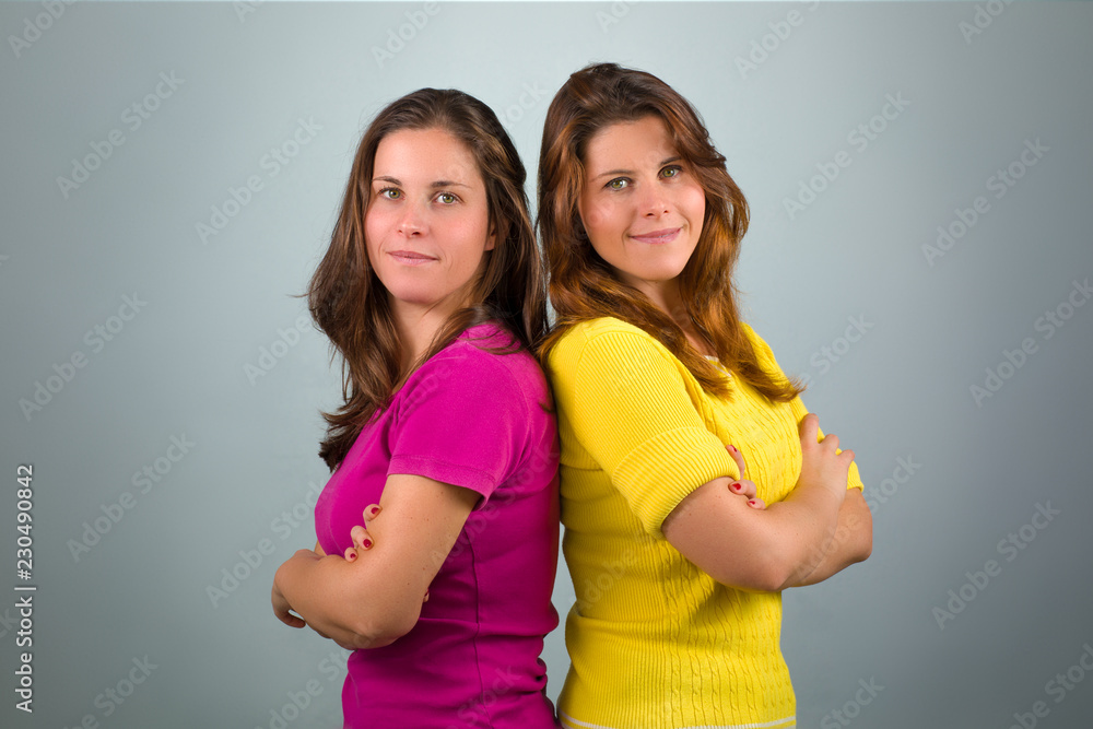 Two Twin Sisters Jumping on Gray Background Two Twin Sisters Jumping on Gray Background
