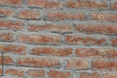 Wall of old uneven brick plastered with cement