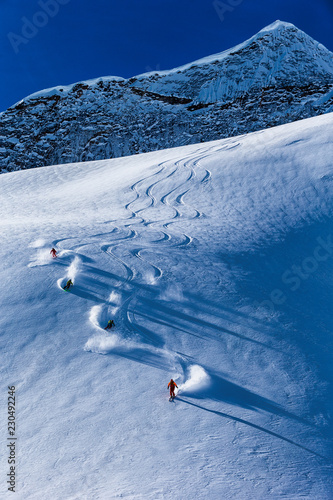 Four skiers skiing down on slope, British Colombia, Canada