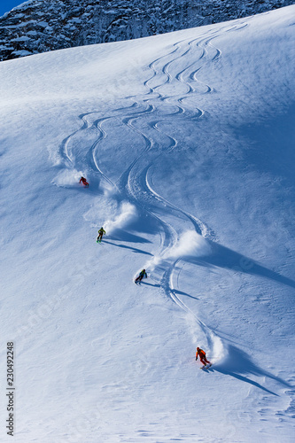 Four skiers skiing down on slope, British Colombia, Canada