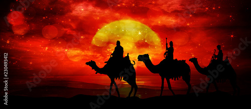 Canvas Print Three kings - wandering in the desert in the light of the setting sun and flashe
