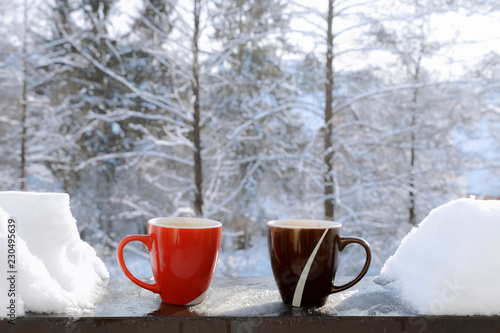 Two cups of coffee on balcony edge and snow