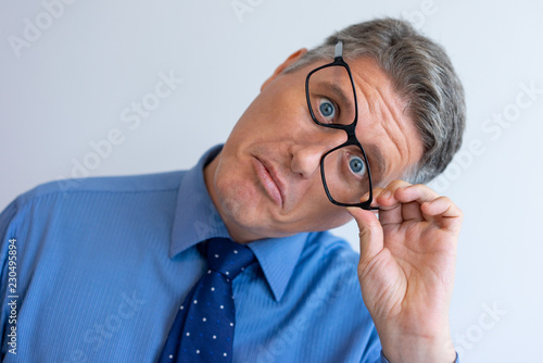 Crazy businessman fooling at camera. Closeup of middle aged Caucasian man touching askew glasses and grimacing. Crazy face expression concept photo