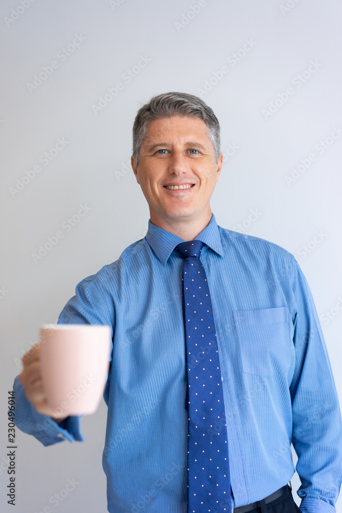 Happy business professional enjoying office morning. Mid adult Caucasian man in shirt and tie showing white cup at camera. Coffee break concept Happy business professional enjoying office morning. Mid adult Caucasian man in shirt and tie showing white cup at camera. Coffee break concept