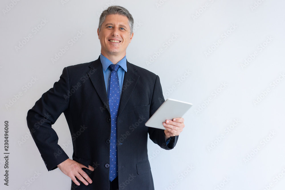 Happy businessman enjoying perfect connection. Content middle aged Caucasian man in jacket holding tablet and smiling at camera. Mobile internet concept