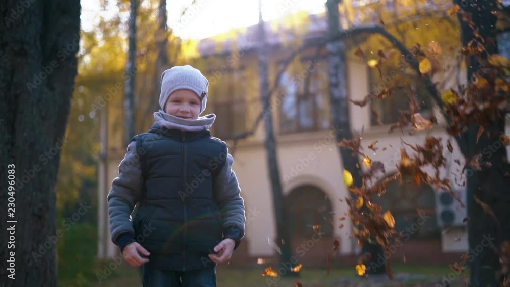 Kid throws yellow leaves in autumn park. Kid throws yellow leaves in autumn park.