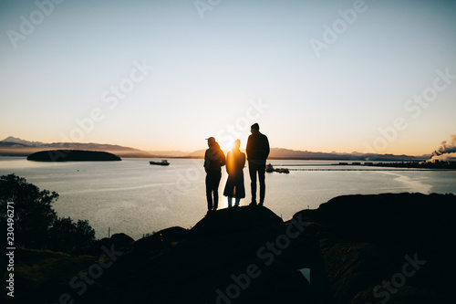 Three people standing on a rock admiring the view