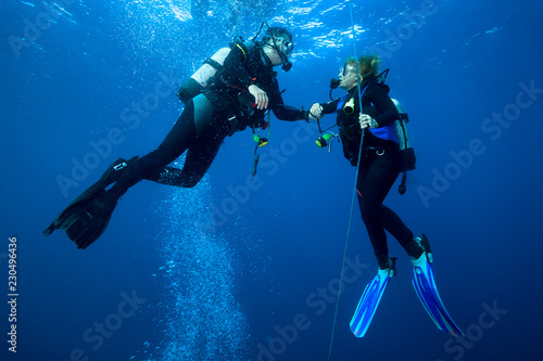 Obraz na plátne Happy couple scuba divers  hovering together on a safety stop