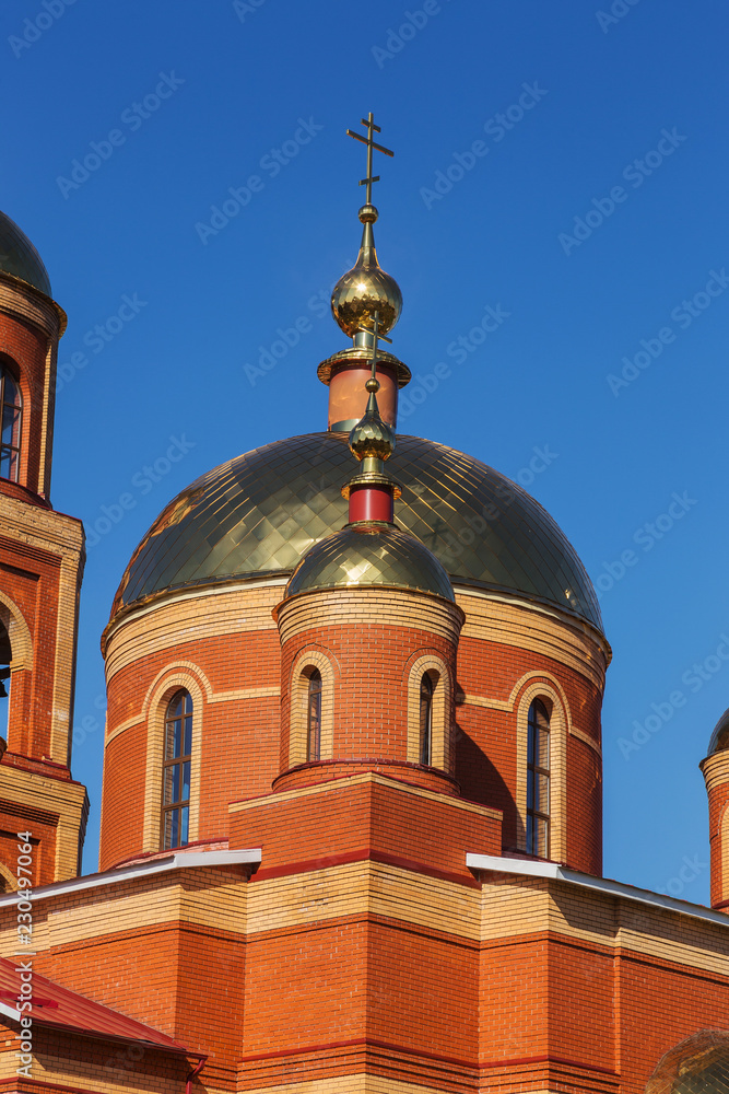 Russian Orthodox Church on the background of blue sunny sky. Orthodox church golden domes and crosses. Church of the New Martyrs and Confessors of Belgorod. Belgorod, Russia 2018